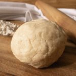 Ball of sourdough discard pastry crust on a board with some flour and a rolling pin
