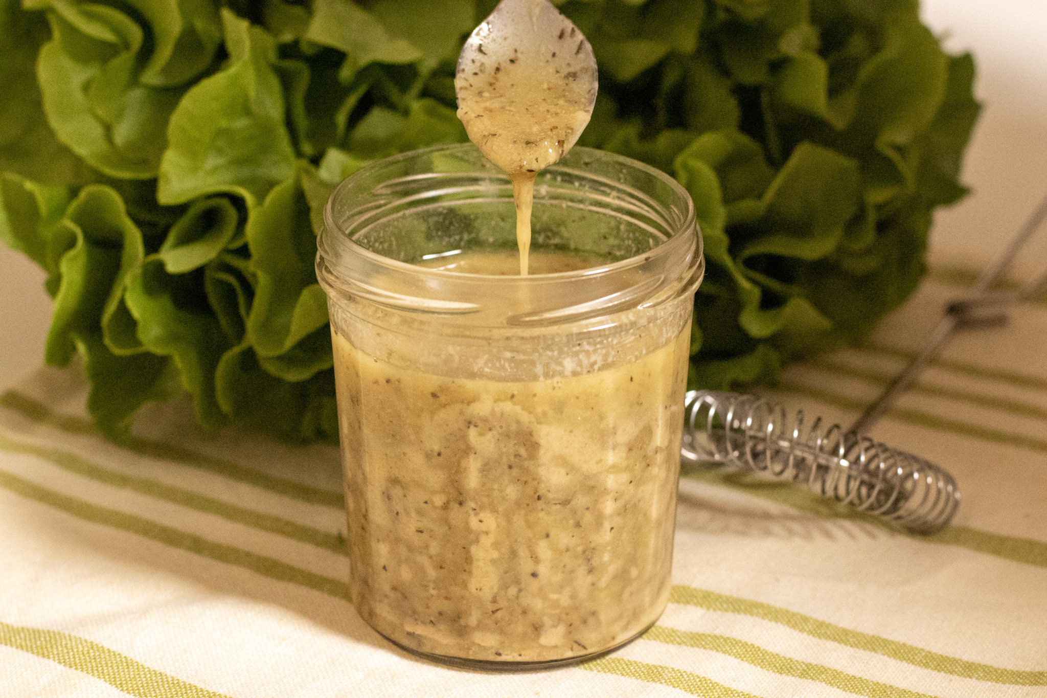 Apple Cider and Herb Vinaigrette in a jam jar with dressing dripping from a spoon