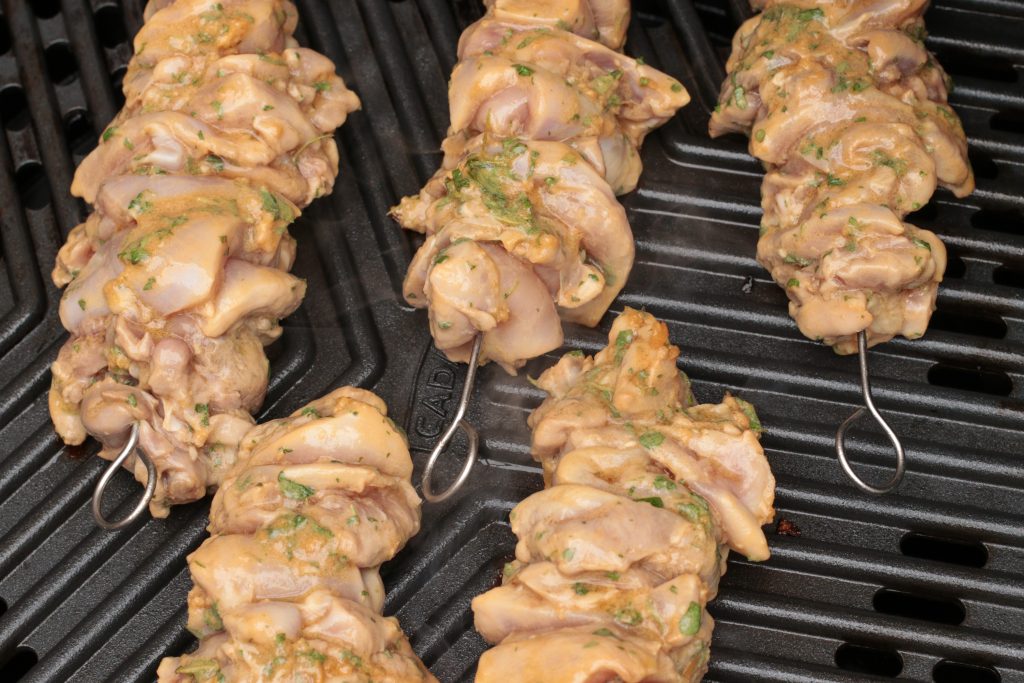 uncooked chicken skewers marinated with lemon and garlic an herbs on a bbq