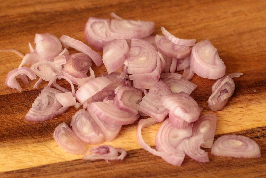 Finely sliced shallots on a wooden board