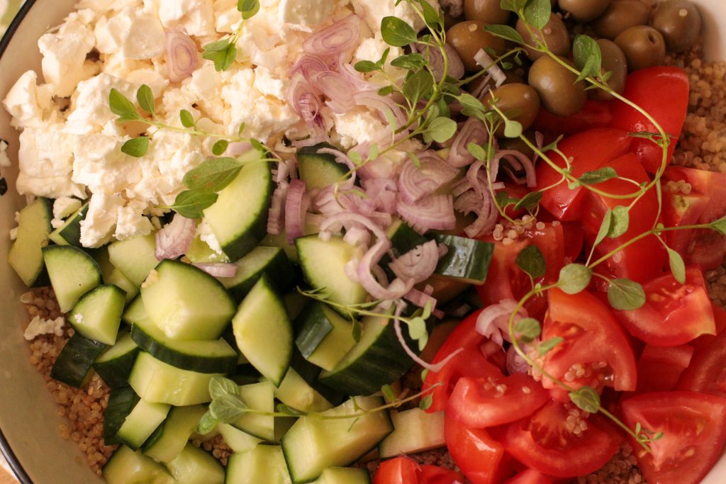 Close-up of chopped tomato, cucumber, and feta salad ready to mix with quinoa