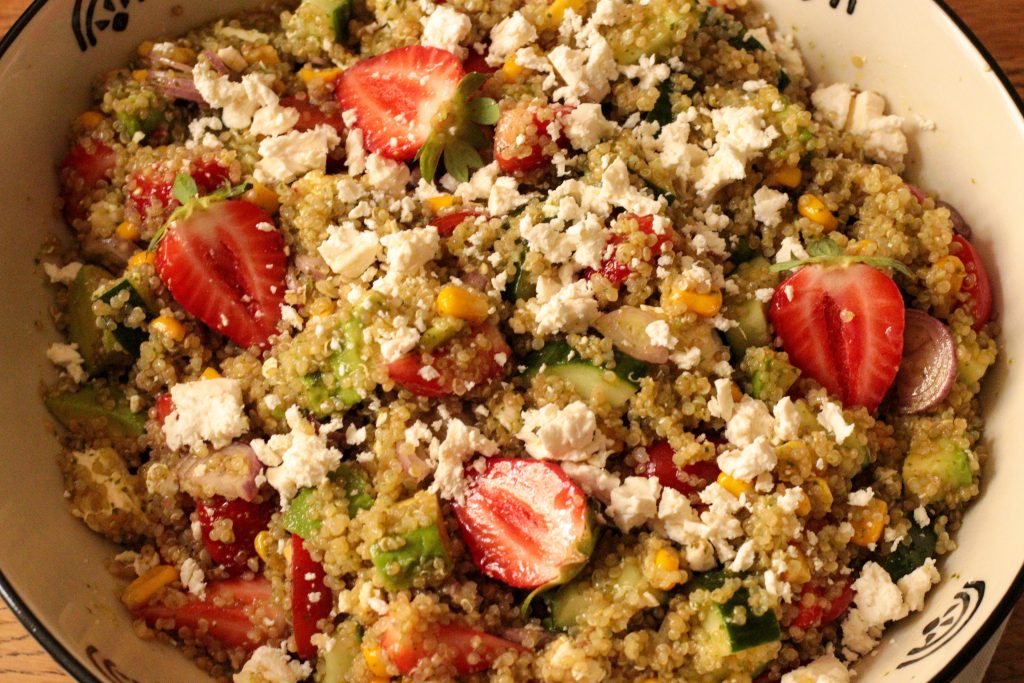 Close up of quinoa salad with strawberries tossed together with sweet basil dressing and topped with feta
