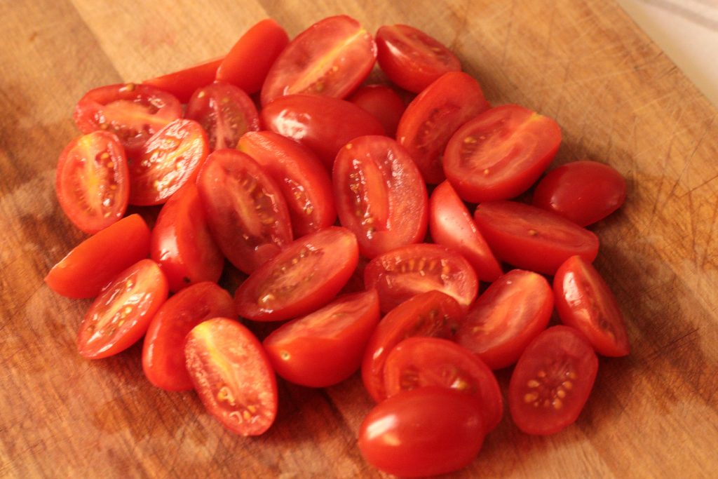 cherry tomatoes halved on a wooden board
