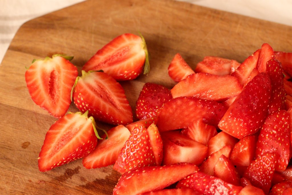 strawberries halved and quartered on a wooden board