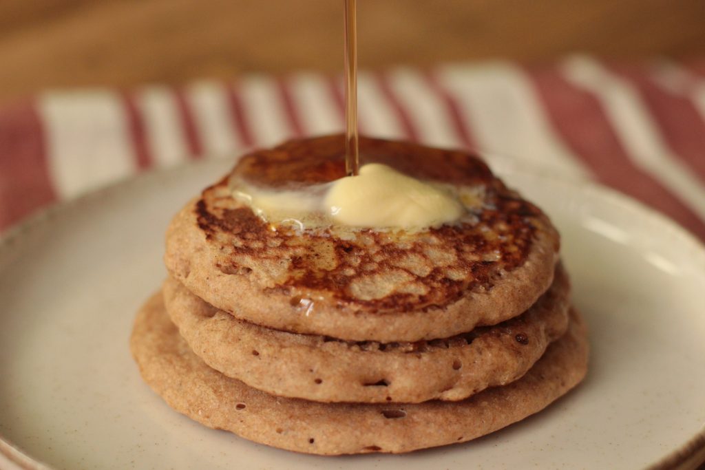 Sourdough Discard Pancakes with Fresh Milled Flour with butter and maple syrup being drizzled