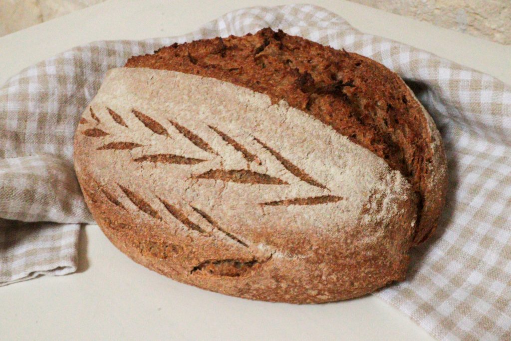 whole wheat artisan loaf with fresh milled flour on a checked tea towel