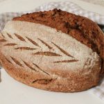 whole wheat artisan loaf with fresh milled flour on a checked tea towel