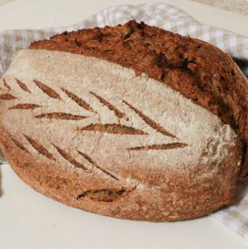whole wheat artisan loaf with fresh milled flour on a checked tea towel