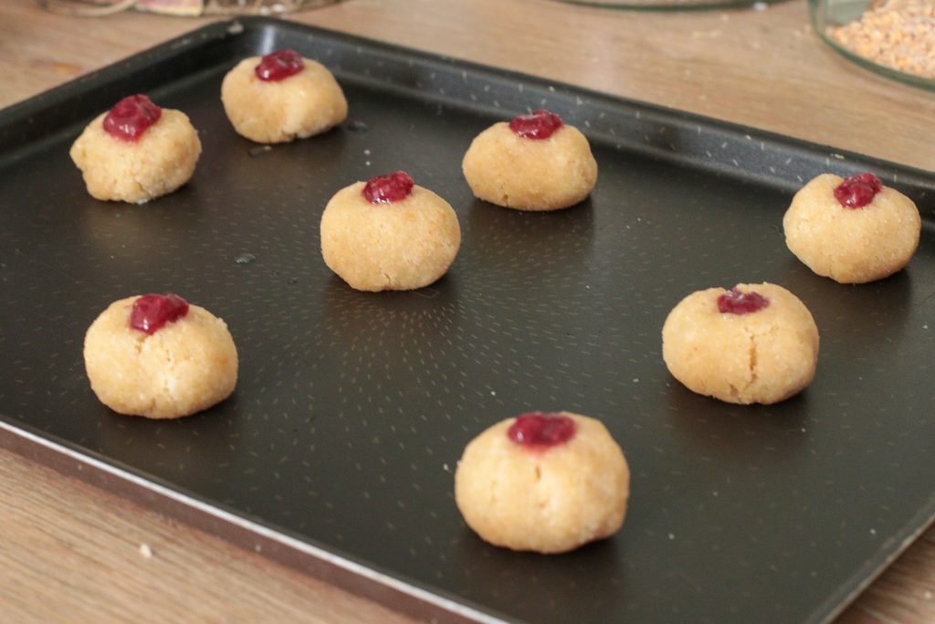 biscuits non cuits à la confiture de framboise sur une plaque de cuisson