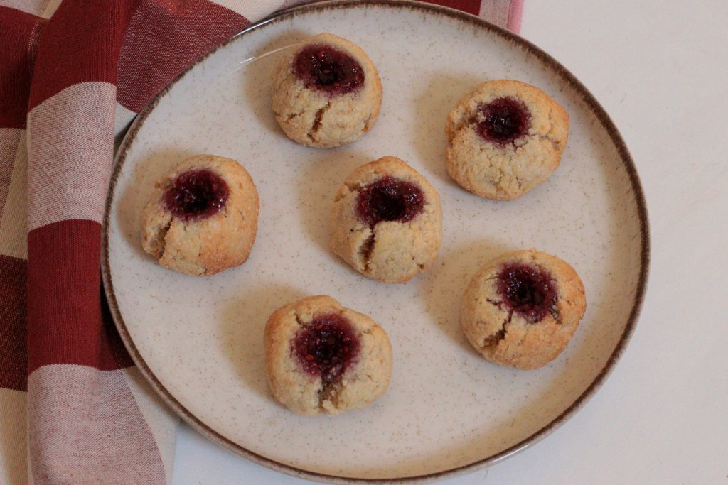 biscuits aux framboises et aux amandes sur une assiette avec un torchon rouge et crème