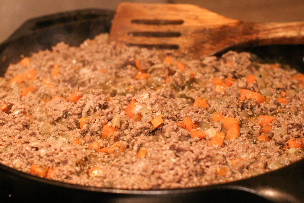 Viande, carottes et oignons dorés dans une poêle en fonte