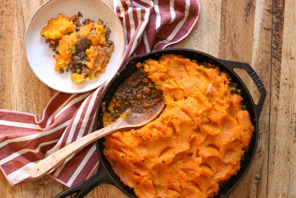 tarte à la courge butternut dans une poêle en fonte, vue d'en haut avec une petite assiette servie