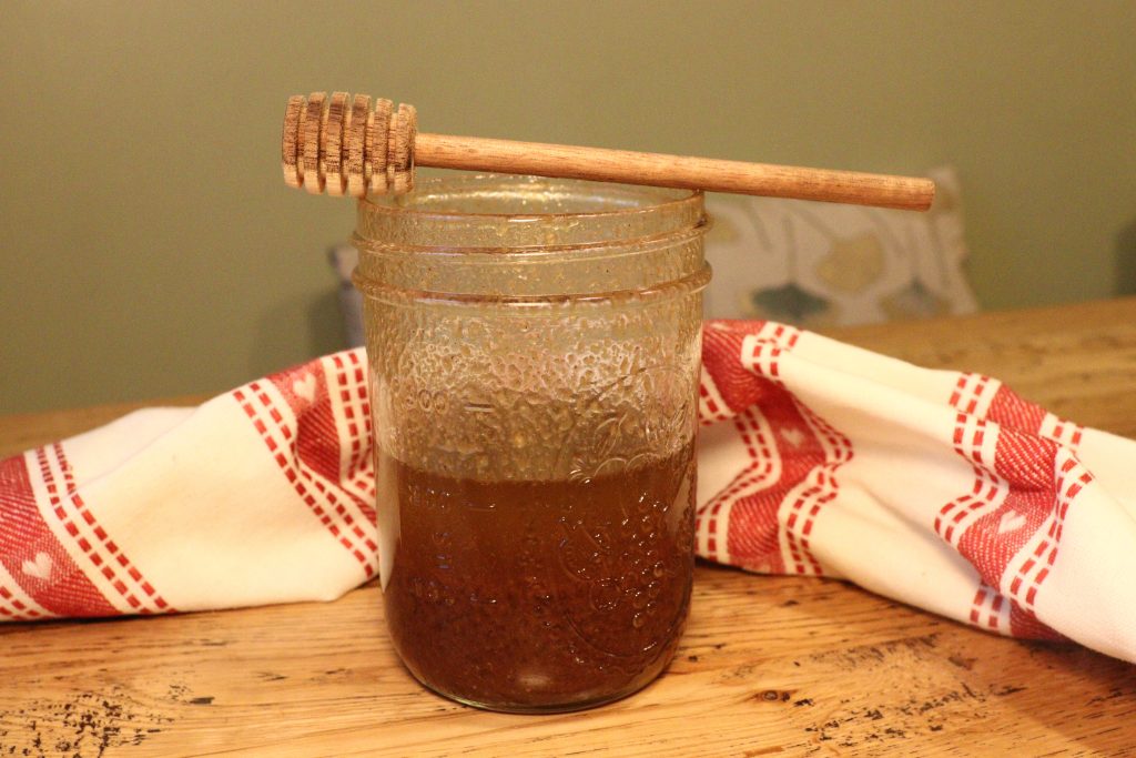 Christmas Spiced Vinaigrette in a mason jar with a honey spoon on top