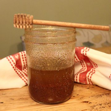 Christmas Spiced Vinaigrette in a mason jar with a honey spoon on top