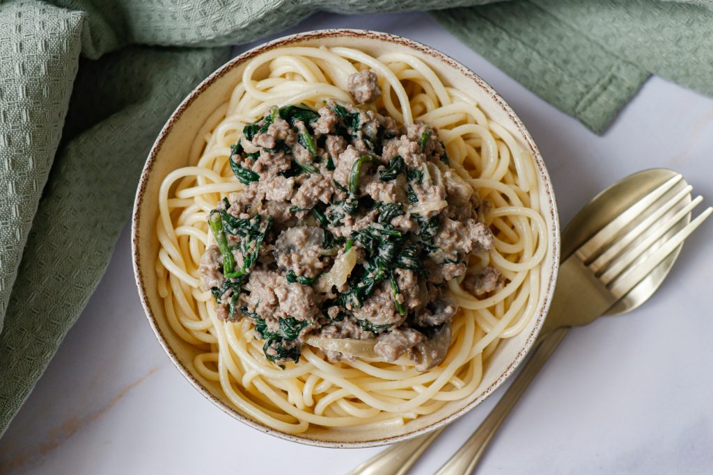 Ground beef stroganoff of a white table with a green tea towel in the background