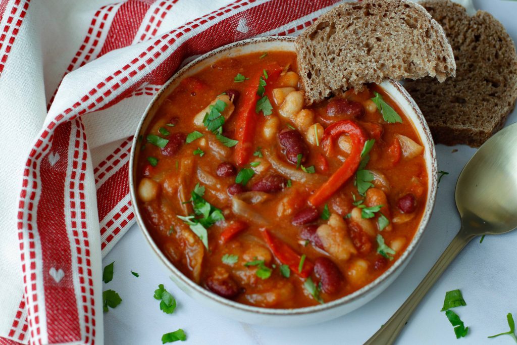 bowl of simple bean stew with a slice of whole grain bread on the side