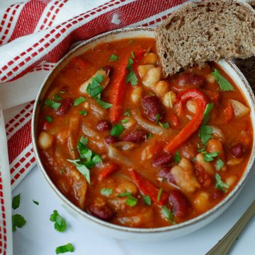 bowl of simple bean stew with a slice of whole grain bread on the side