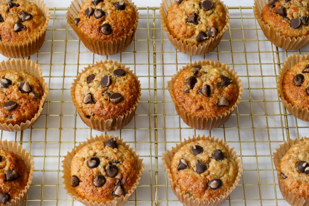 12 Sourdough banana oat muffins with chocolate chips on a wire rack